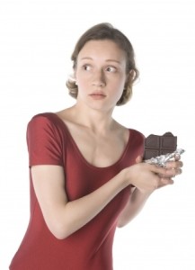 Woman eating choc guilty look